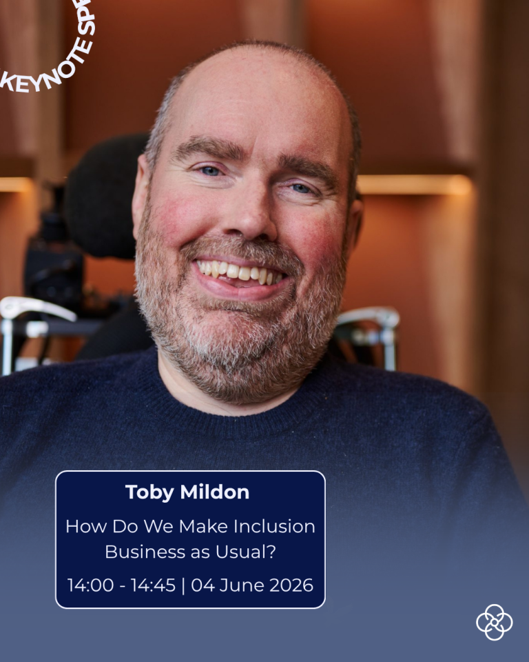 Promotional image showing Toby seated in a wheelchair, facing the camera with teeth visible, wearing a dark top. The background is an indoor setting with warm lighting and wooden wall panels. Overlaid text reads: ‘KEYNOTE SPEAKER’, ‘Toby Mildon’, ‘How Do We Make Inclusion Business as Usual?’, and ‘14:00–14:45 | 04 June 2026’.